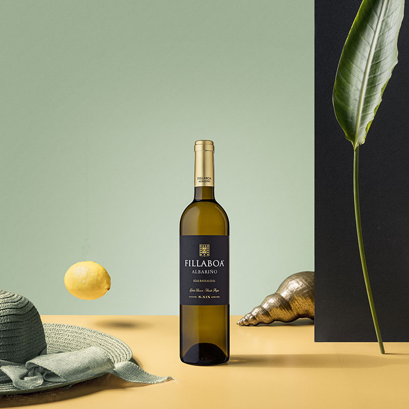 Botella de Fillaboa Albariño junto a un limón, una concha y una hoja verde